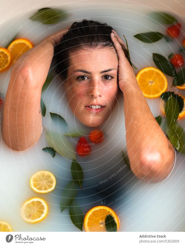 Woman taking bath with strawberry in mouth woman citrus orange slice milk eat wet hair spa female healthy rejuvenate procedure bathroom body care fruit water