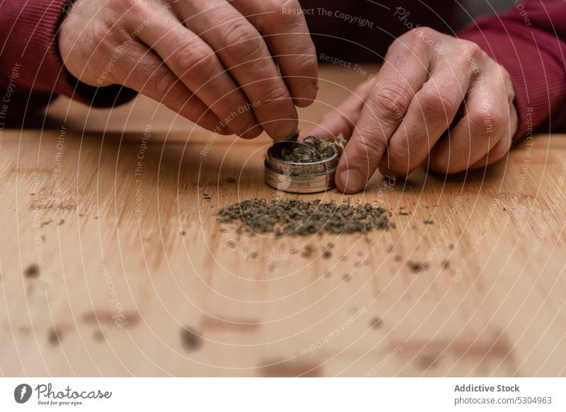 Crop man adding dried cannabis in marijuana grinder - a Royalty Free Stock  Photo from Photocase