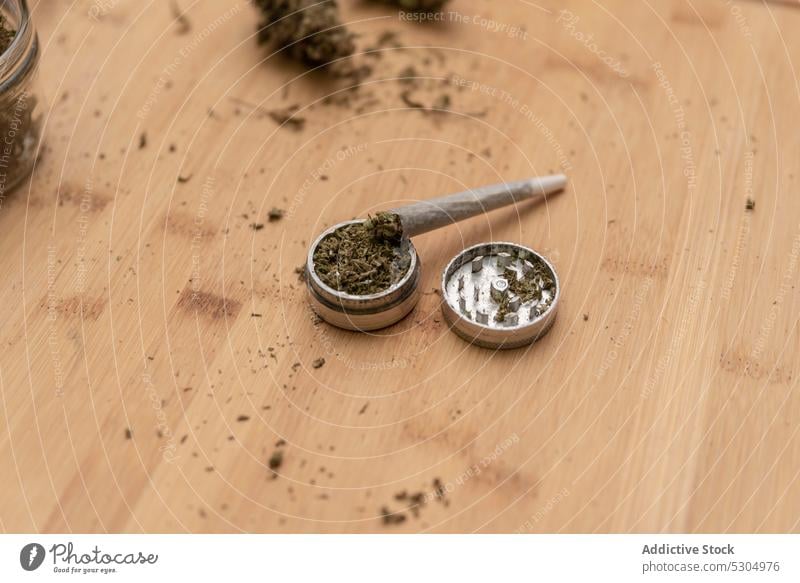 Cannabis joint placed on metal grinder cannabis marijuana weed ganja natural dried plant herb narcotic cannabinoid hemp legalize blunt rolled drug leaf dope cbd