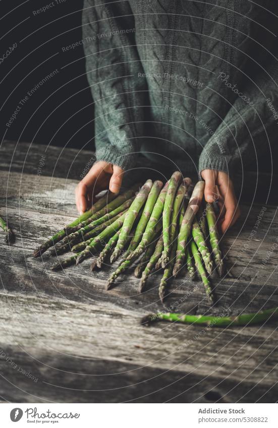 Crop person with bunch of asparagus on table fresh natural organic healthy vegetable ripe prepare wooden stem sweater green plant vitamin vegetarian harvest