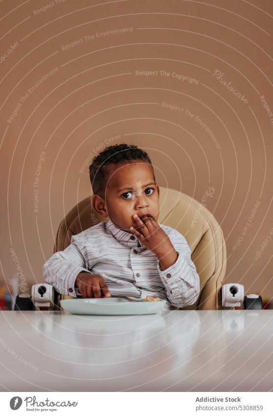 Adorable boy eating tasty breakfast toddler food delicious cute adorable portrait child black african american ethnic meal snack yummy hungry appetite lunch