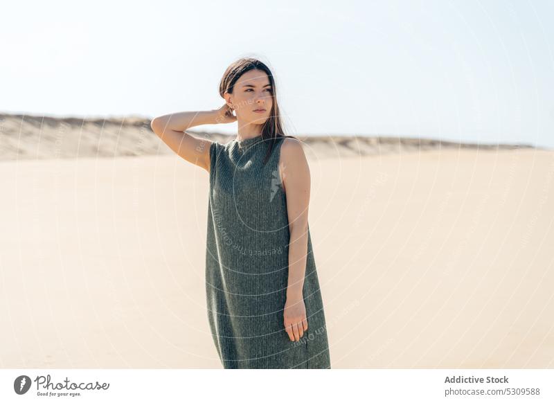 Charming woman in dress standing on sandy beach sea touch hair vacation summer nature rest calm style female cloudless vieux boucau les bains france coast