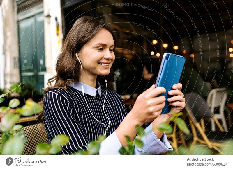 Woman using tablet on cafe terrace woman positive headphones watch food tea teapot croissant online internet female device gadget breakfast smile happy