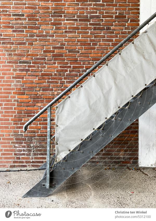 A metal staircase with privacy screen in front of a patched clinker facade Stairs External Staircase Metal steps Facade mended Brick wall brick wall