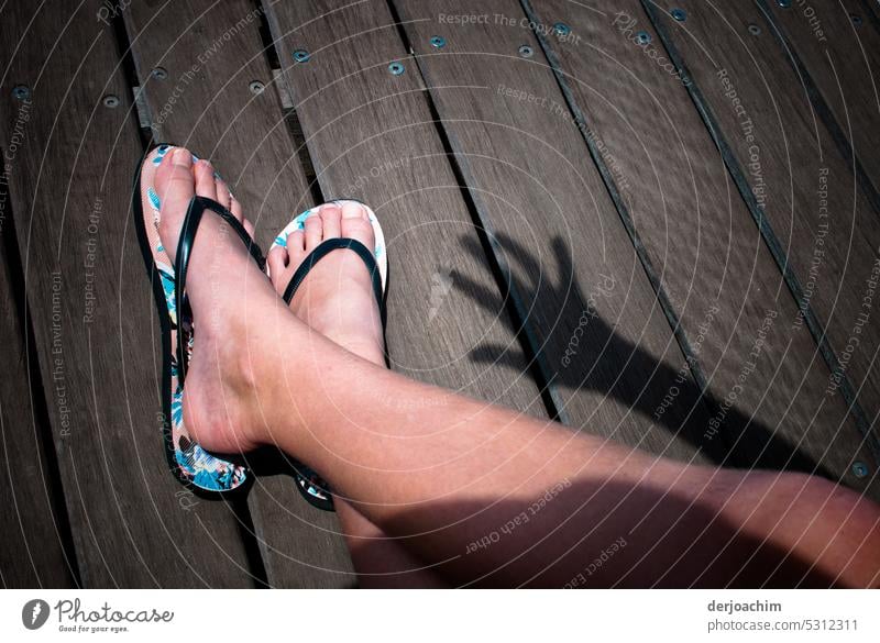 Two bare feet in sandals in the sunshine with a hand shadow. - a Royalty  Free Stock Photo from Photocase