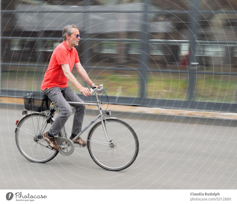 Grey haired gentleman with bicycle dynamically riding in the city Best Ager Cycling Climate protection turnaround Driving Means of transport sustainability