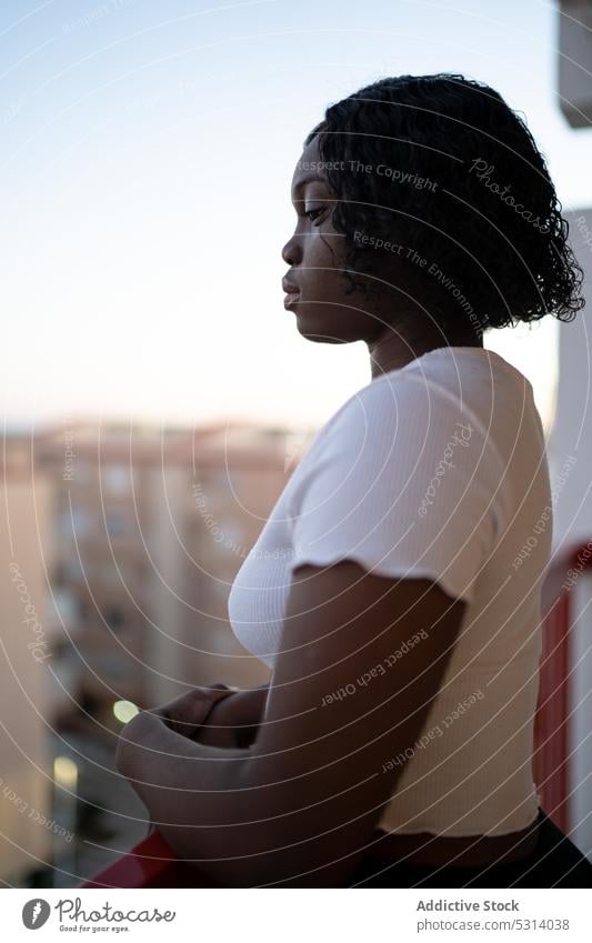 Black woman admiring cityscape on balcony terrace admire railing building appearance urban female curly hair street ethnic calm top afro tranquil