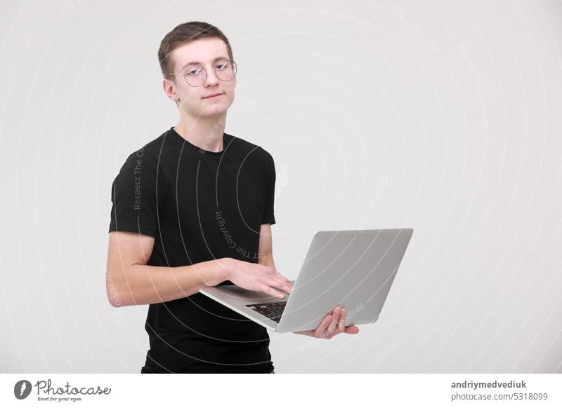 Distance learning online education. portrait of a young man in a black T-shirt with glasses with a laptop on a white background. copy space business computer