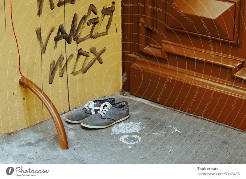 A pair of shoes stands in the entrance of the house in front of graffiti and door from founder period Footwear Couple sneakers Comfortable Entrance turned off
