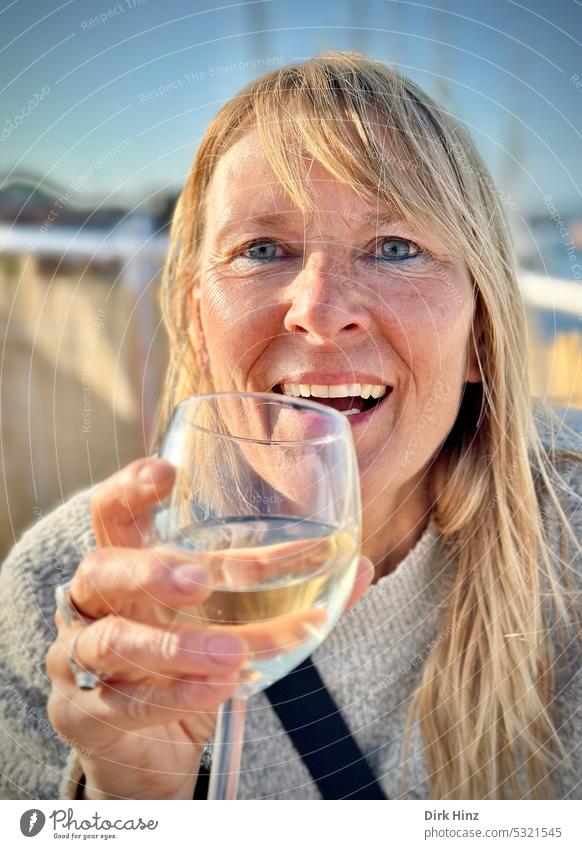 Laughing blonde woman with glass of white wine in hand Woman portrait Human being Looking Looking into the camera Exterior shot Adults Forward Colour photo
