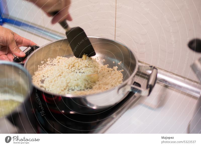 Human hand with a cooking utensil stirring rice with garlic recipe white dish aroma caucasian closeup copy space cuisine delicious diet dinner food fresh