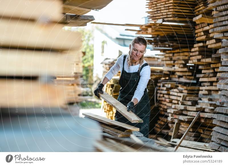 Woman working with wooden planks in a sawmill real people woodshop carpenter entrepreneur expertise craftsperson creativity manufacturing crafts people hobby