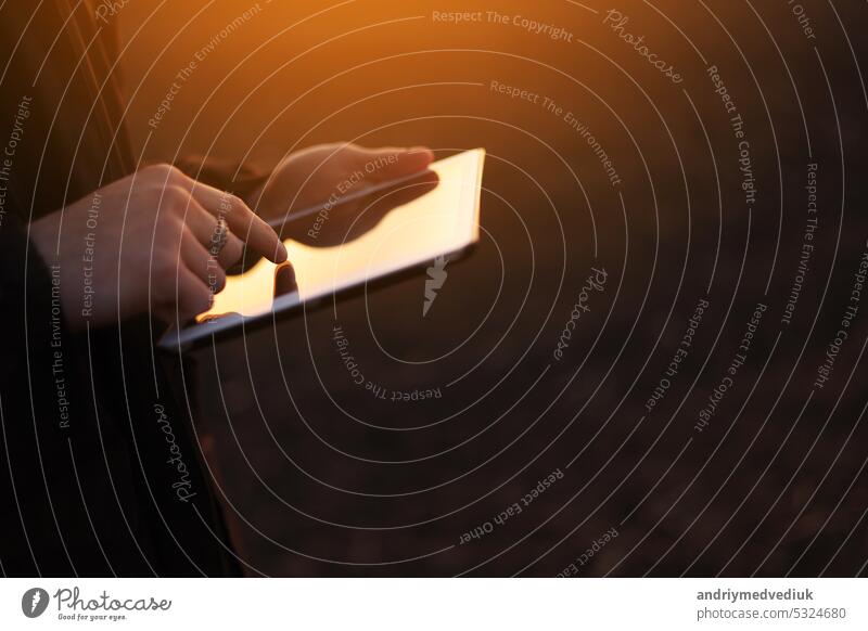 Cropped shot of male farmer's hands use digital tablet on plowed field for control of soil quality, land readiness for sowing crops and planting vegetables. Smart farming technology and agriculture