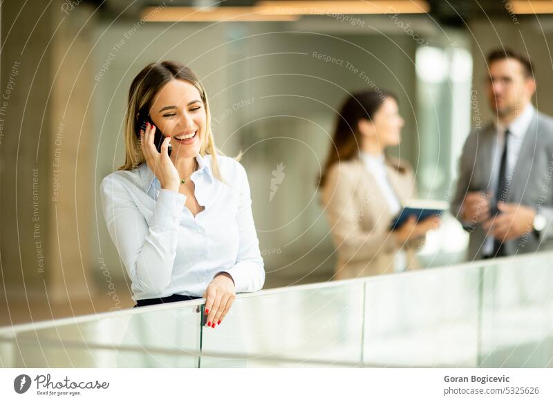 Young business woman with mobile phone in the office hallway adult assistant businessman businessmen businesspeople businesswoman career caucasian colleagues