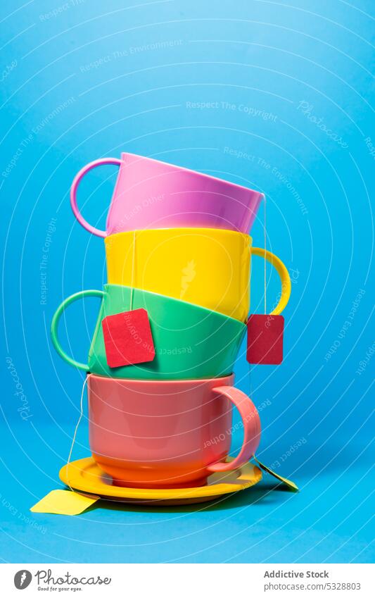 Colorful cups with tea bags on blue background saucer ceramic drink beverage colorful teatime bright porcelain composition design set mug dishware natural vivid