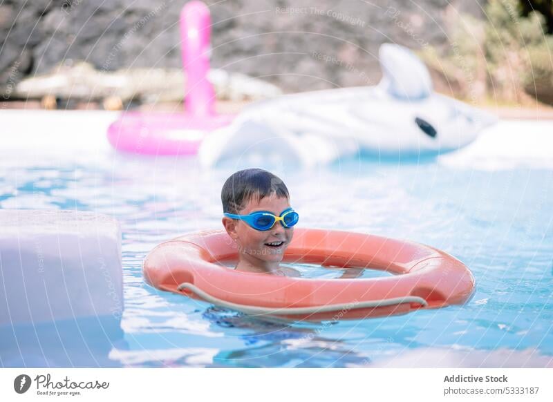 Little kid swimming underwater in pool boy float cheerful inflatable vacation smile happy child childhood summer tube holiday ring resort relax recreation enjoy