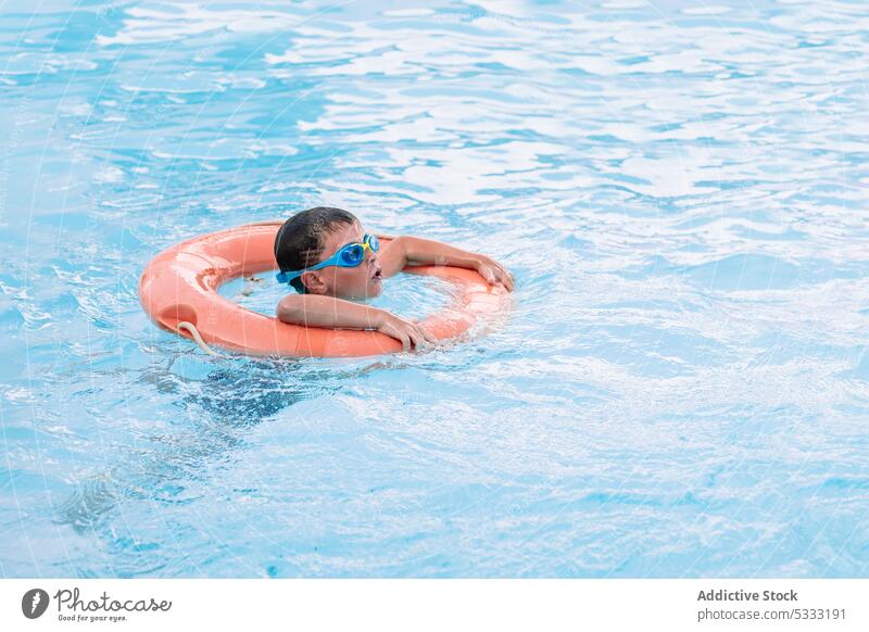 Little kid swimming underwater in pool boy float inflatable vacation child childhood summer tube holiday ring resort relax recreation enjoy rest season activity