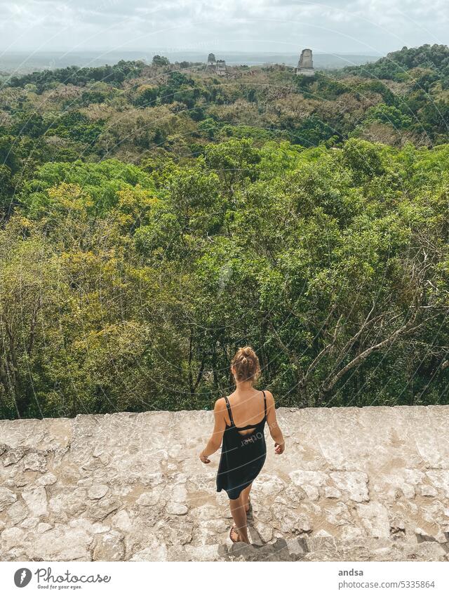 Woman looking at rainforest with temples from above outlook Virgin forest jungles Temple Maya Ancient Manmade structures Historic Archeology from behind Treetop