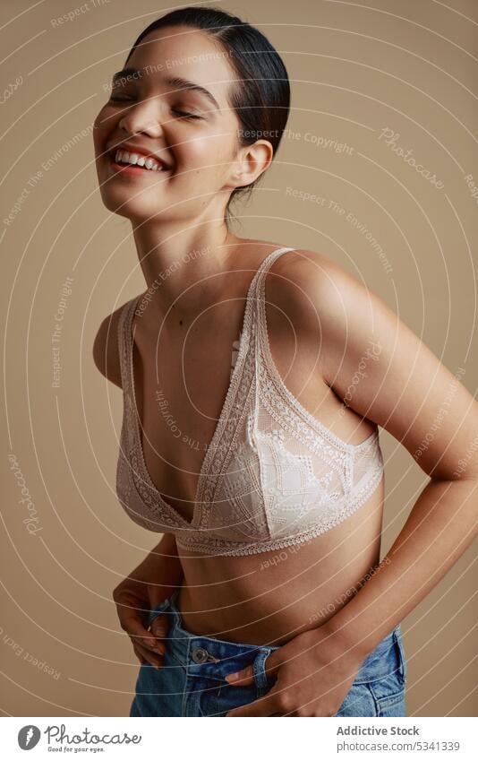 Cheerful woman in underwear smiling with closed eyes smile happy eyes closed positive bra portrait cheerful style jeans female young delight model natural slim