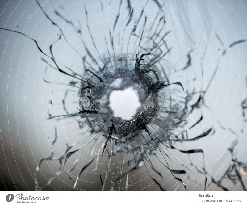 bullet hole in cracked window glass abstract accident background broken broken glass broken window bullet hit closeup color crash crime damage danger deadly