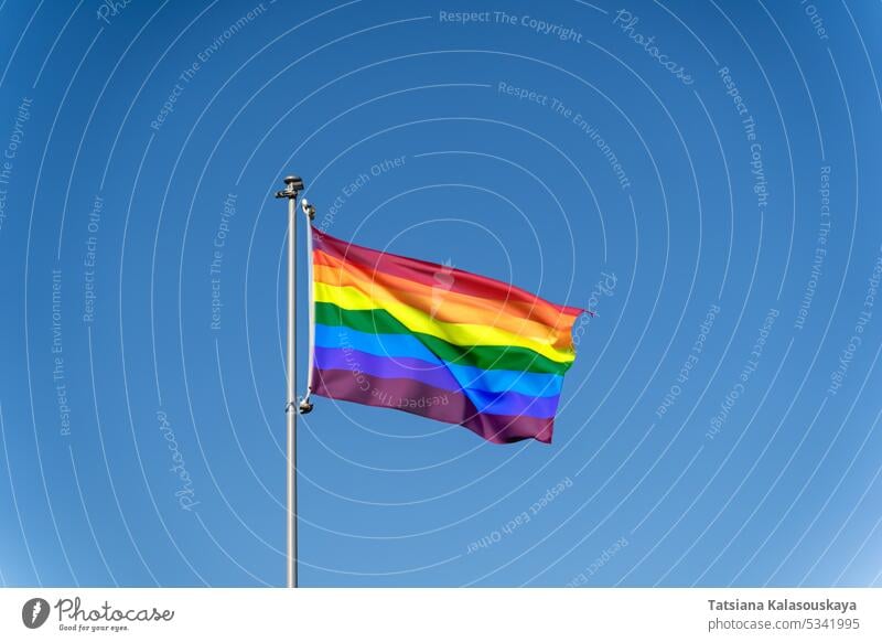 LGBTQ rainbow flag waving against a clear blue sky Rainbow flag Waving Clear Blue sky Pride Equality Diversity Inclusion Celebration Identity Freedom Love