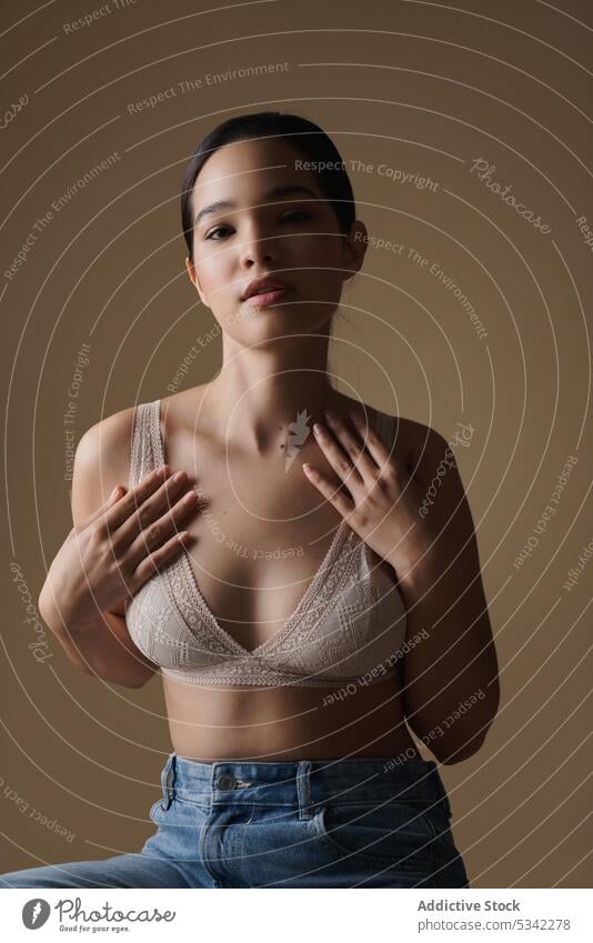 Calm woman in underwear touching chest and looking at camera style model dreamy portrait bra touch chest studio beauty female fashion jeans slim outfit trendy