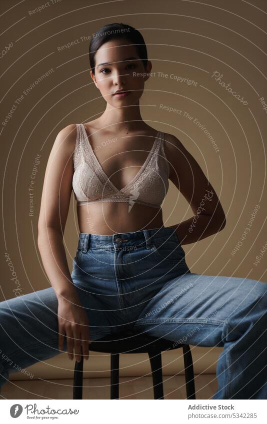 Graceful woman sitting on chair in light studio - a Royalty Free