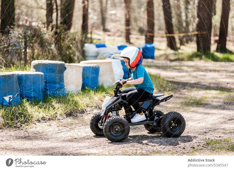 Kid driving power bikes in countryside girl kid motorcycle helmet ride amusement activity rent park child motorbike transport nature cheerful casual smile