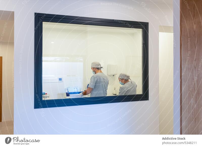 Transparent glass showing doctors in mask working in modern lab specialist laboratory clinic colleague hospital professional uniform medical coworker occupation