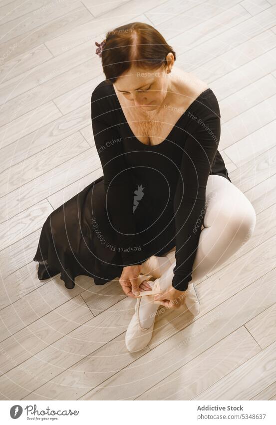Calm woman putting on ballet pointe shoes in studio ballerina prepare dancer put on focus choreography rehearsal grace top view pensive talent female practice