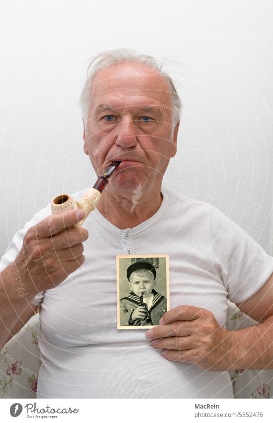 Man with pipe and a picture from childhood days 60-70 years old more adult Pensioners Child children's photo stop To hold on Pipe portrait Retro sits Undershirt