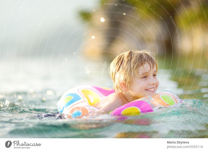 Little boy swimming with colorful floating ring in sea on sunny summer day. Cute child playing in clean water. Family and kids resort holiday during summer vacations.