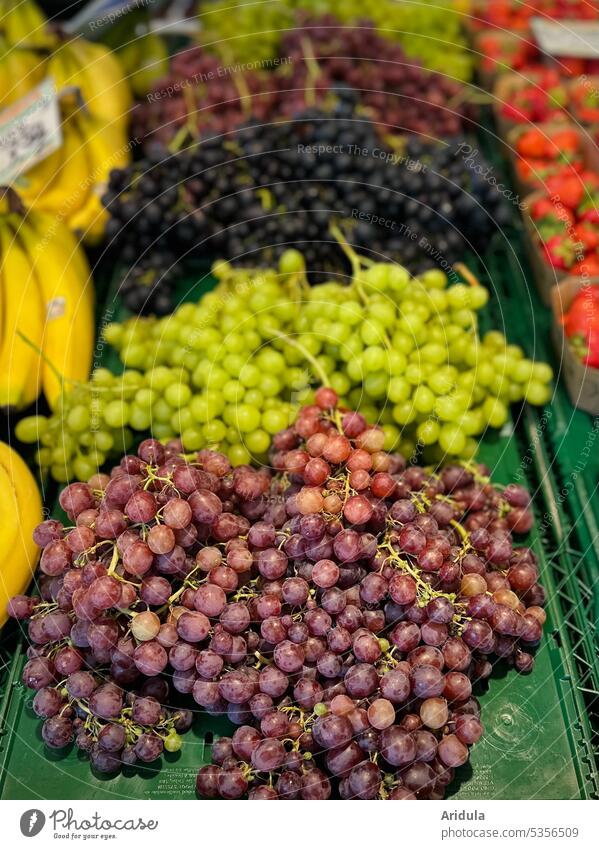 Weekly market | various grapes between bananas and strawberries Bunch of grapes Green Red Blue seedless Bananas Strawberry Strawberry hulls Markets