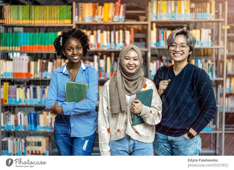 Group of diverse students smiling at camera while standing together in a library real people teenager campus positive exam knowledge confident academic adult