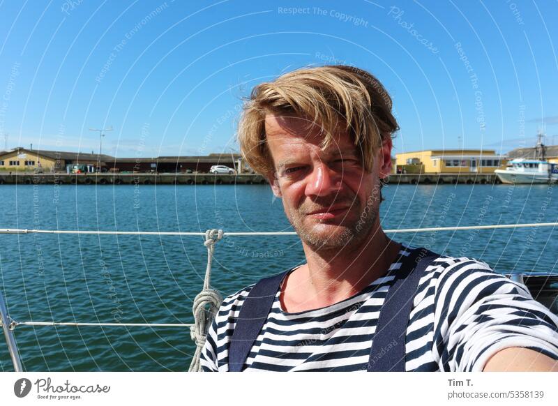 a man in a striped shirt on a ship in the harbor Harbour Man Denmark Water boat Exterior shot Sky Maritime Colour photo Blue Day Ocean Navigation Blonde Summer