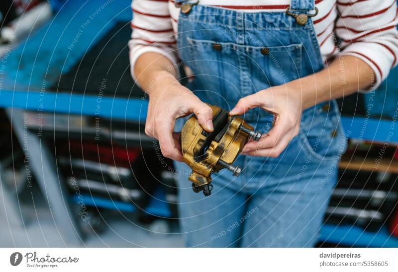 Mechanic woman checking caliper brake system in front of workbench unrecognizable female mechanic disc disk factory garage work bench holding hand working