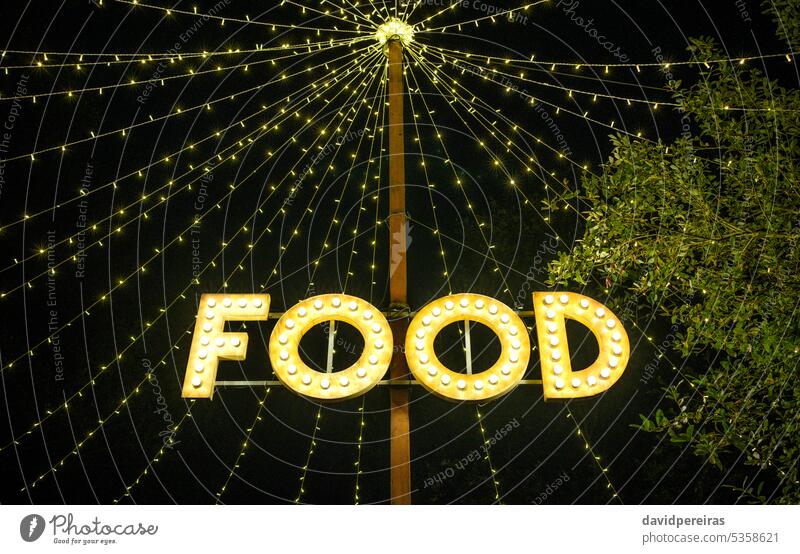 Signboard with word food made with light bulbs hung on wooden post under light garlands signboard signal lighting night trees treetop letter nature summer
