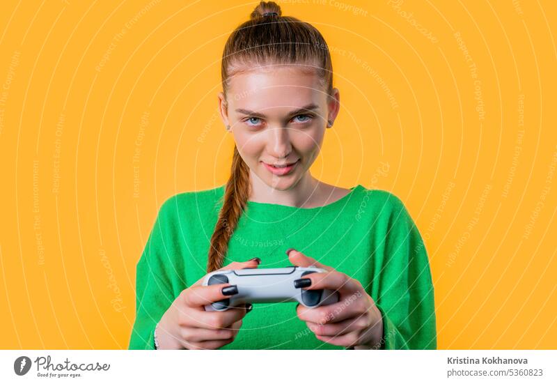 Young woman playing online video game, console TV with joystick yellow backdrop arrow button closeup computer control controller electronic enjoy entertainment