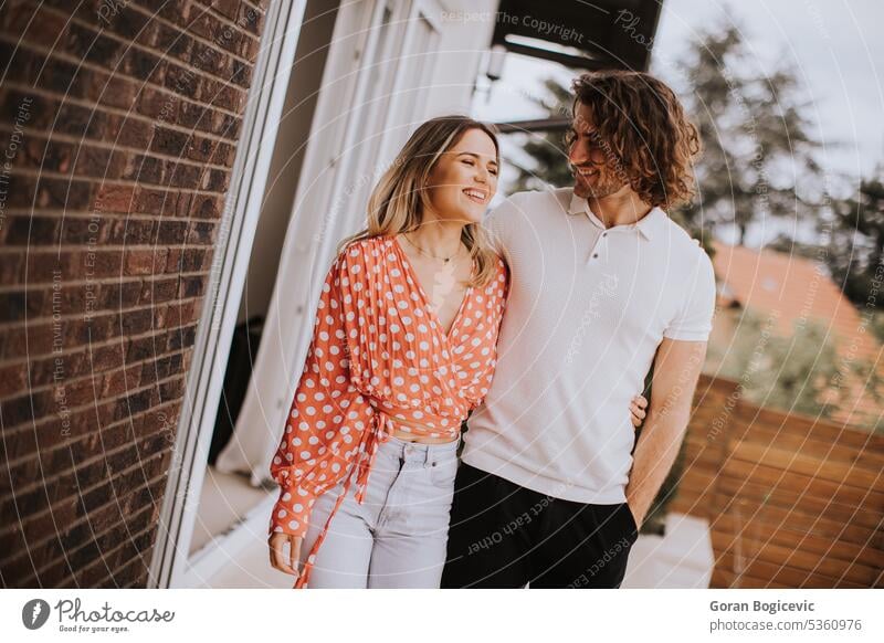 Smiling young couple in love walking  in front of house brick wall adult beautiful casual caucasian cheerful cute facade female happiness happy home lifestyle