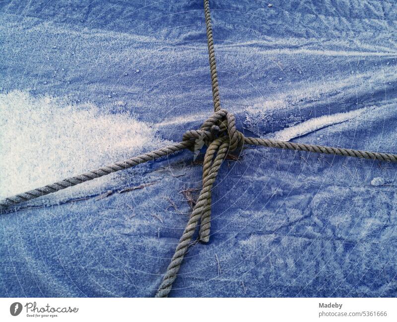 Boat stowage over an icy blue tarpaulin made of plastic in winter on a boat trailer in Oerlinghausen near Bielefeld on the Hermannsweg in the Teutoburg Forest in East Westphalia-Lippe