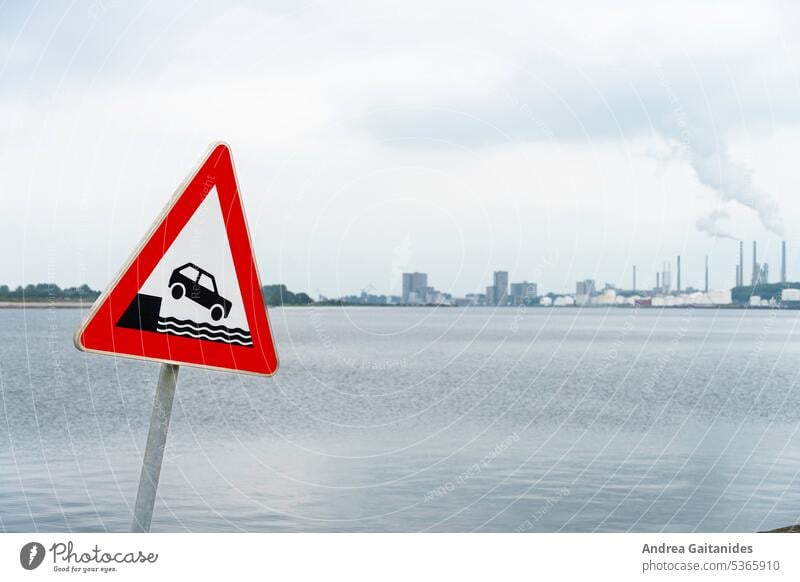 Traffic sign Attention shore on the left side of the picture, water and harbor building defocused in the background, horizontal Warning sign Road sign esteem