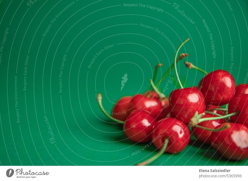 Red cherries on a green background sweet cherries Cherry Summer Fruit Fresh Delicious Copy Space top Copy Space left Advertising Advertising Industry Poster