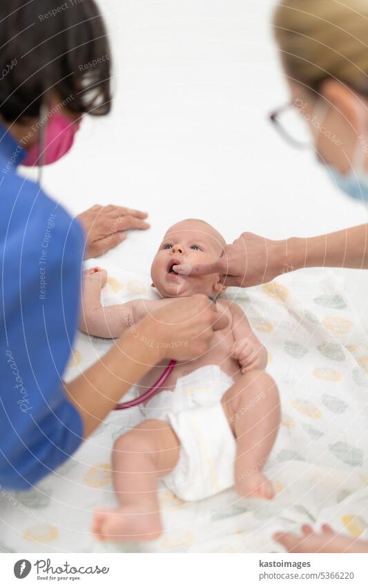Baby lying on his back as his doctor examines him during a standard medical checkup baby infant boy pediatrician stethoscope heartbeat childhood medicine clinic