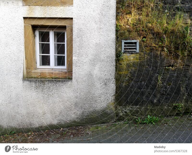 Washed out old facade in pastel colors with white wooden muntin window and frame made of natural stone in the old town of Oerlinghausen near Bielefeld on the Hermannsweg in the Teutoburg Forest in East Westphalia-Lippe