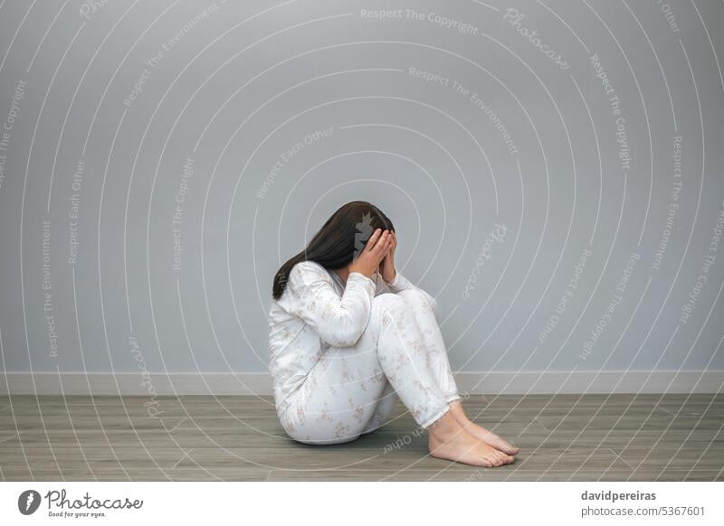 Woman with mental health problems covering her face with hands unrecognizable desperate woman anxiety sad disorder depression sitting floor copy space lonely
