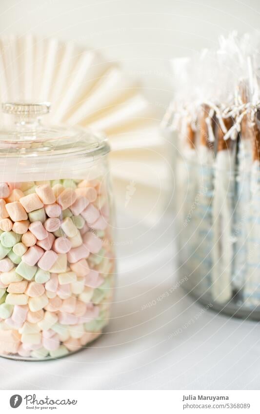 Glass jar of colorful pastel mini marshmallows on a dessert table glass jar white background treat celebration party occasion small pink green yellow orange