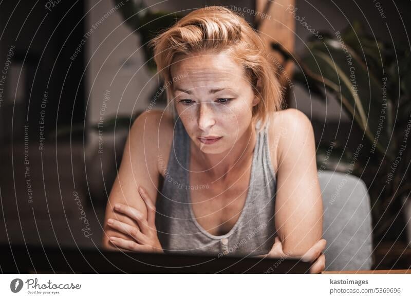 Casual woman working late at night reading something on computer screen. Working from home concept. portrait Human being Adults Portrait photograph Young woman