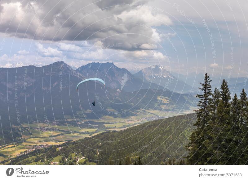 Paraglider floats over mountain landscape Man paraglide Sky Paragliding Flying mountains Peak Forest Landscape fields spruces Clouds Freedom Alps