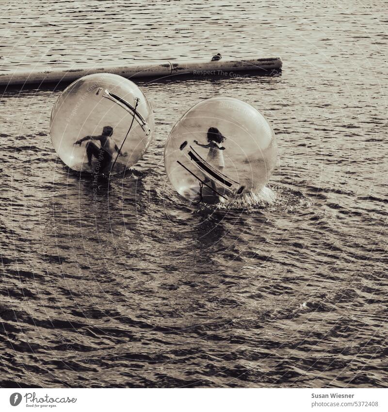 A boy pursued by a girl running in Aqua Balls on the water - Monochrome children action Exterior shot Water Movement Boy (child) Girl Happy fun