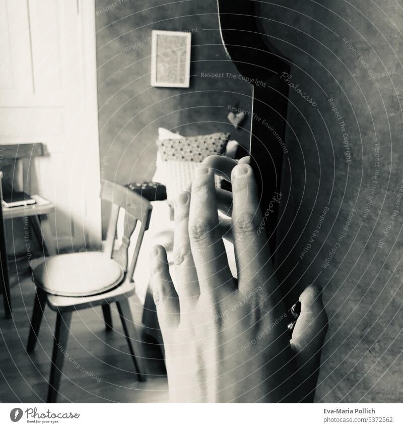 a hand on a mirror, in the mirror is an abandoned room with chair and bed in gray Empty Mirror reflect Light White Room nobody Bed Bedroom Interior Frame